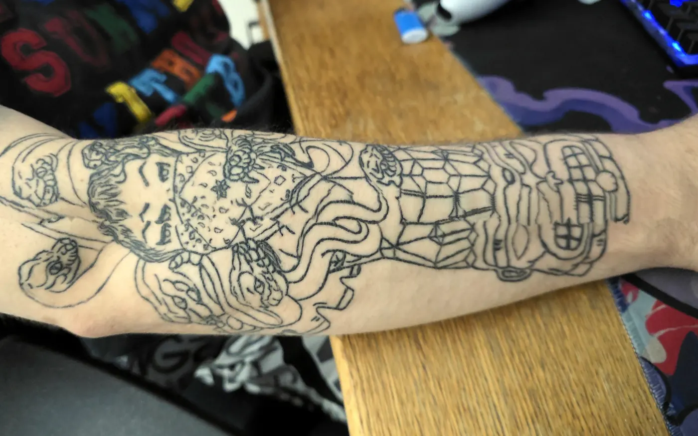 Large detailed linework tattoo across an arm.