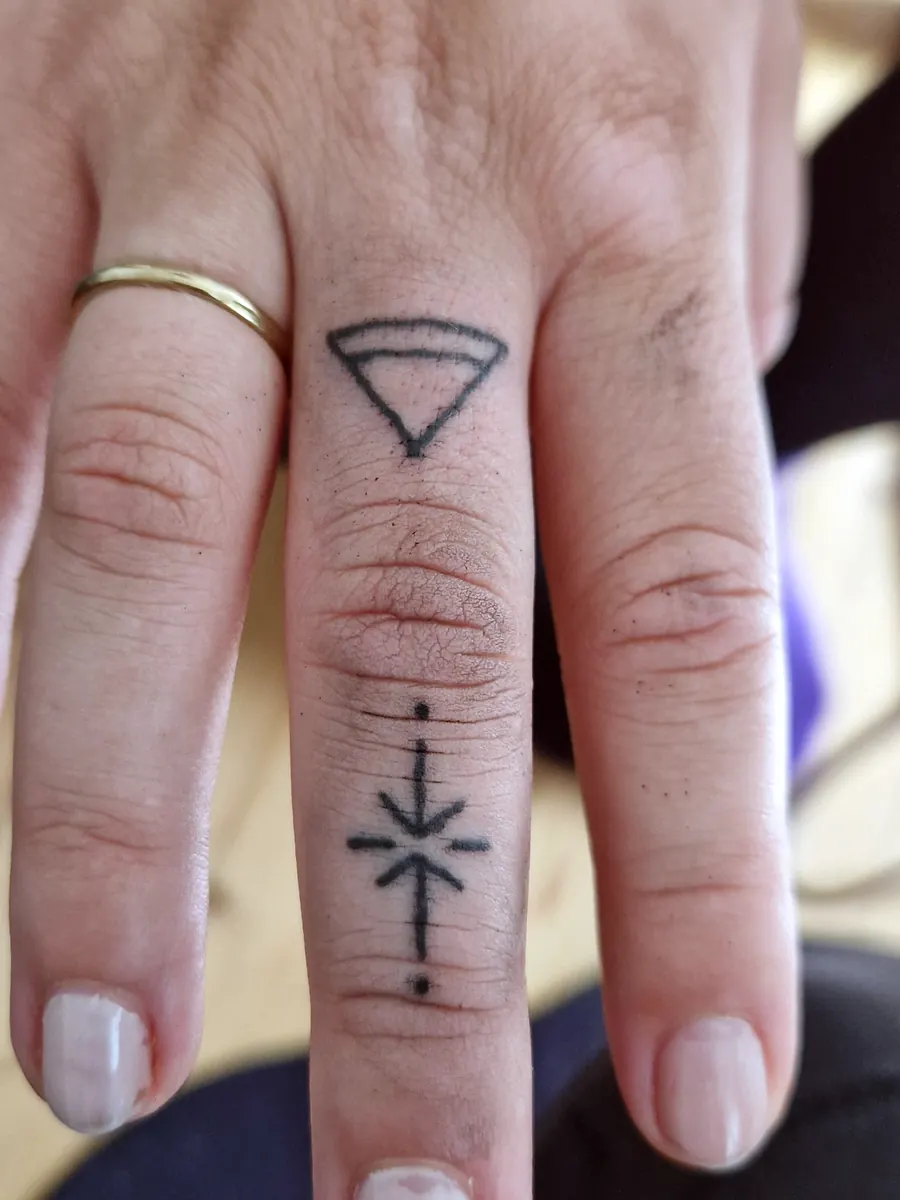 Minimal symbol tattoos on a finger.
