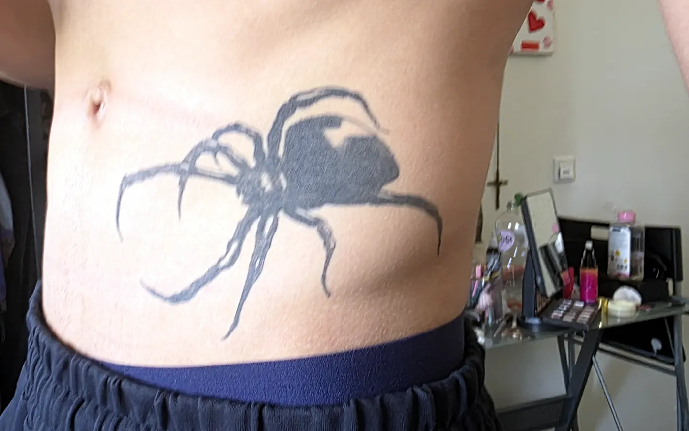 Large black spider tattoo on the side of the torso.