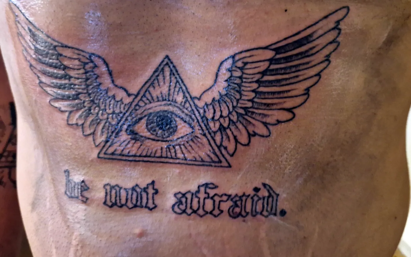 Winged eye tattoo across the stomach.